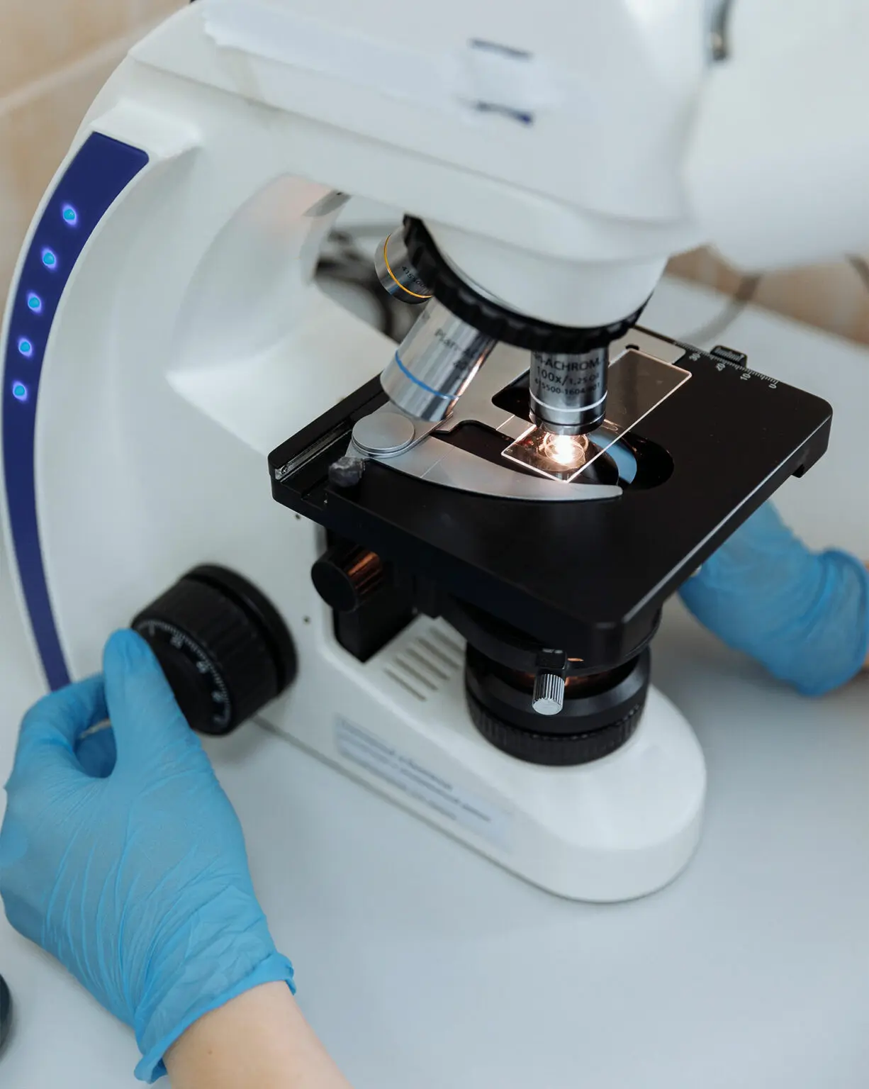 Osoba patrząca przez mikroskop laboratoryjny.
